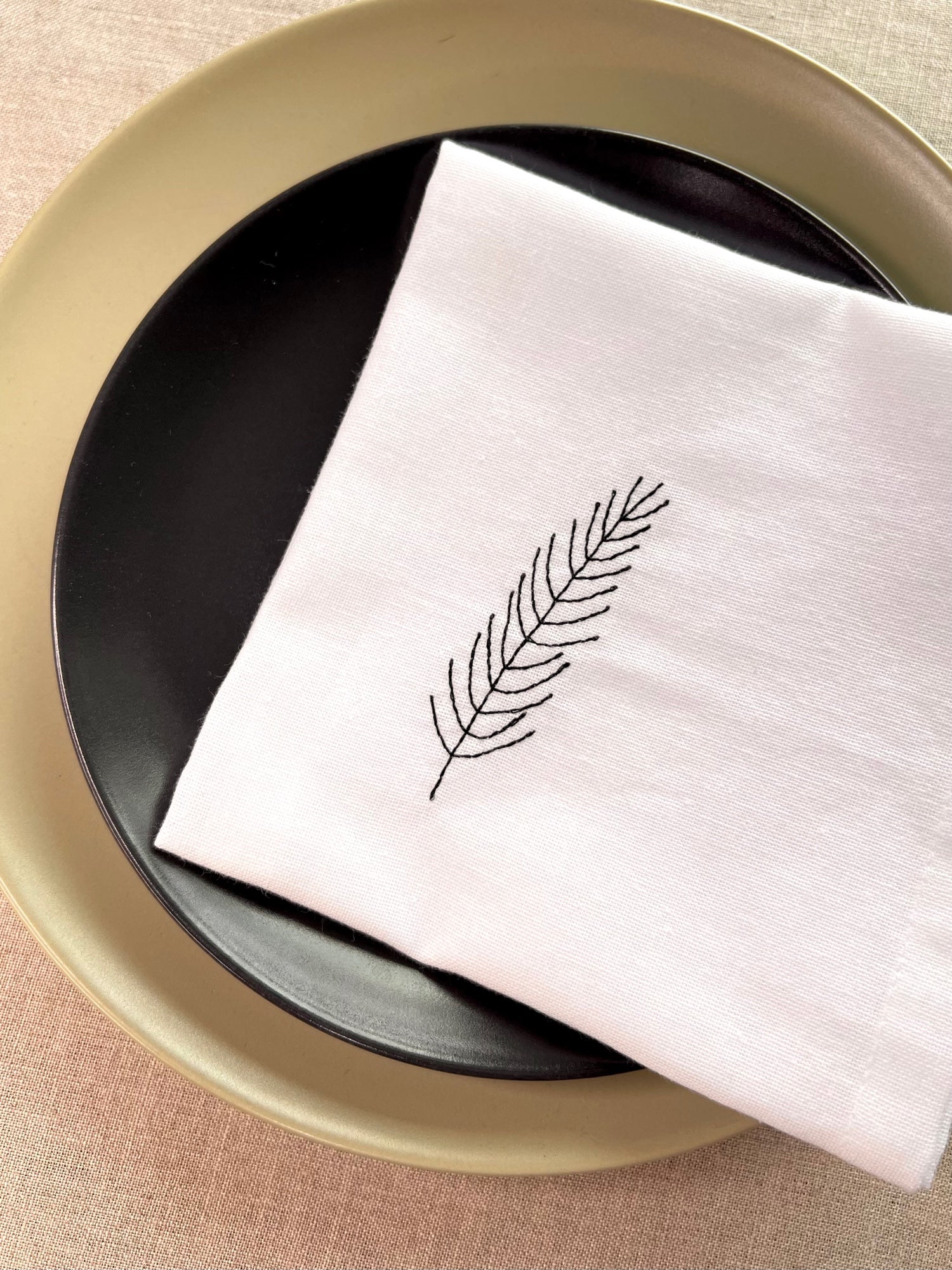 White linen napkin embroidered with fir branch design for holiday dining