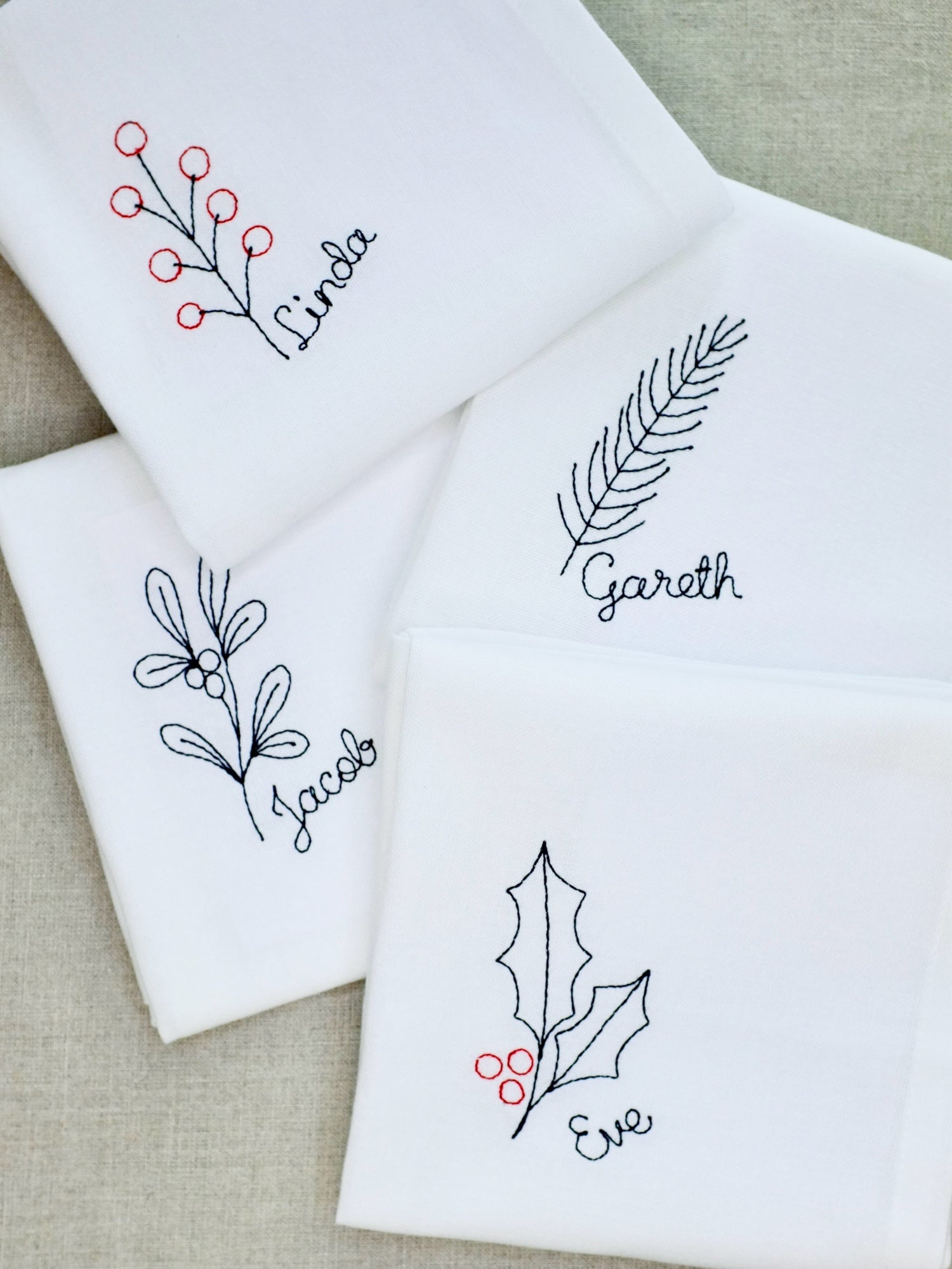 This set of embroidered cotton napkins includes four seasonal designs: mistletoe, holly, winter berries, and fir. Each napkin is personalised with a stitched name, creating a unique place setting and a lasting keepsake. Ideal for Christmas entertaining or