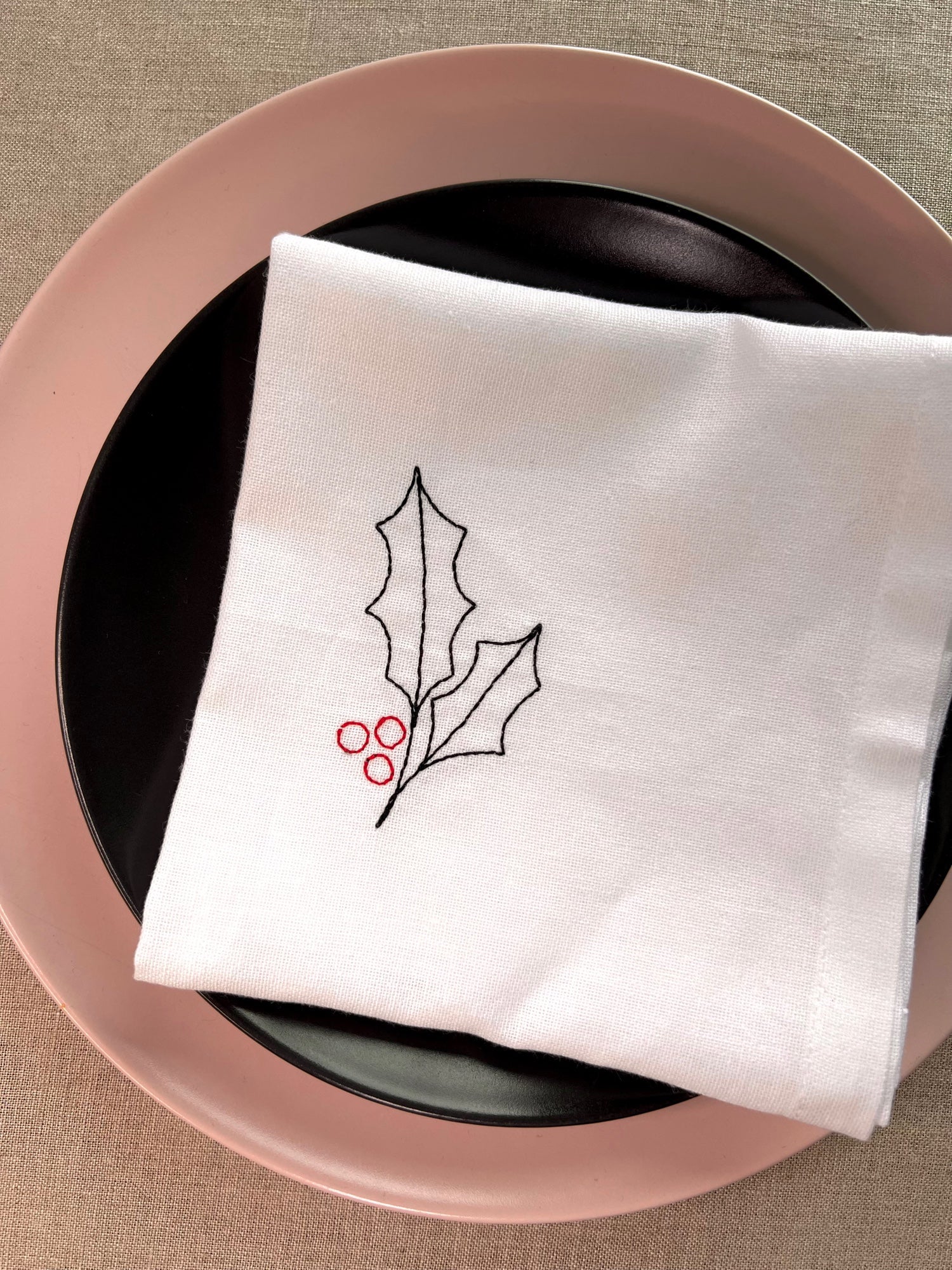 Christmas napkin featuring embroidered holly leaves with red berries