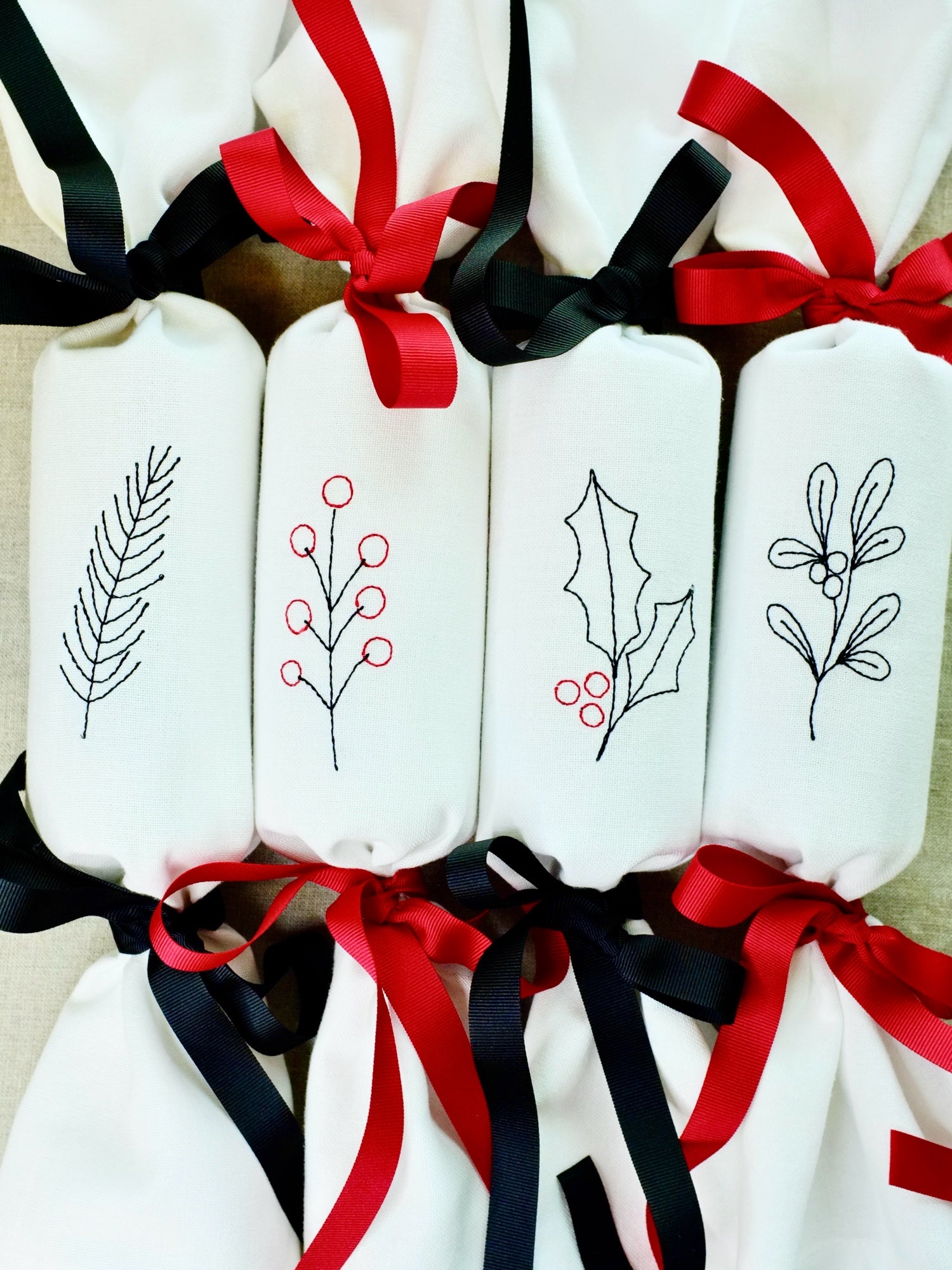 Set of four winter foliage reusable cotton napkin embroidered Christmas crackers wit red and black bows