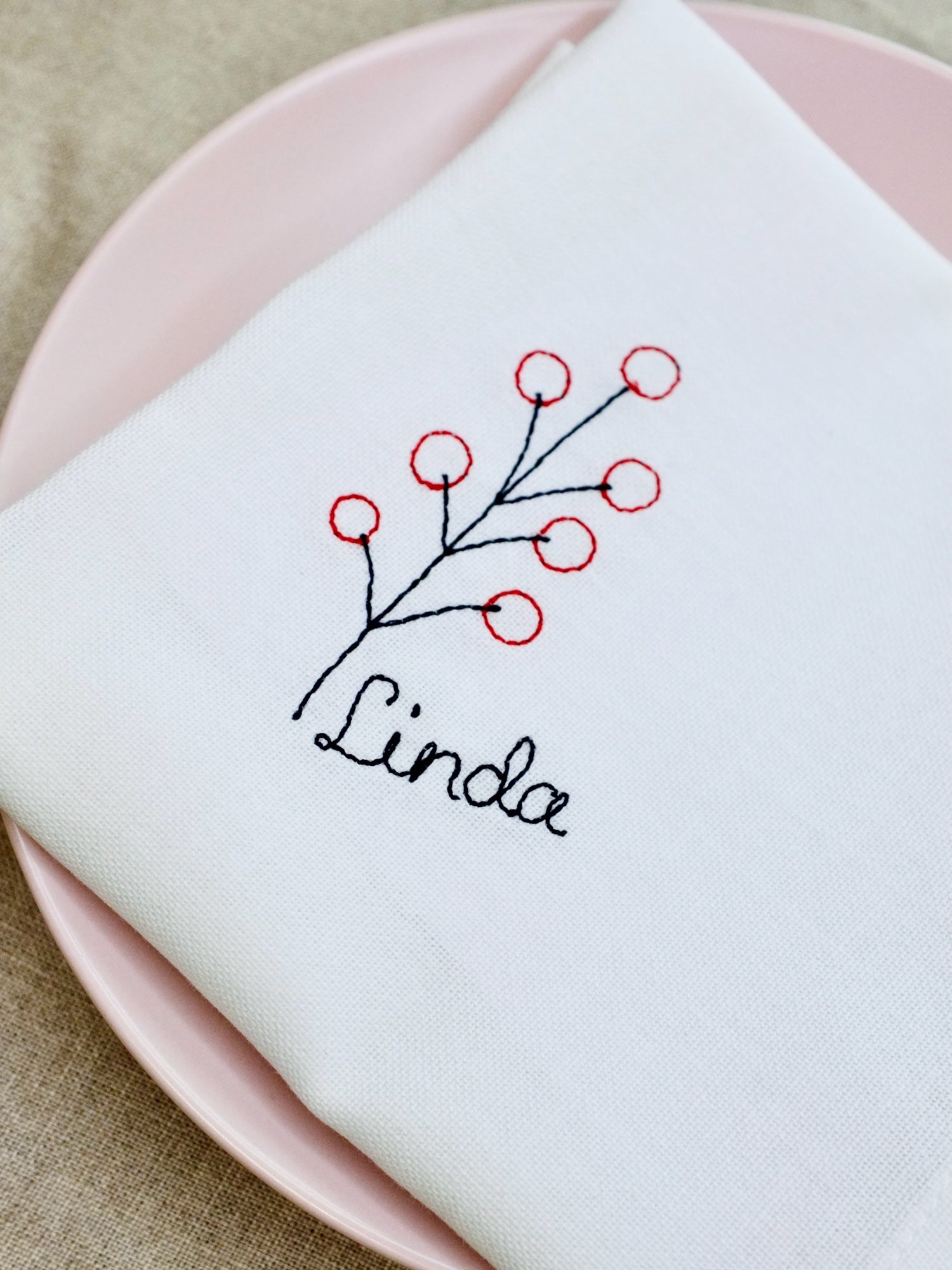 A crisp cotton napkin decorated with a stitched sprig of red berries and finished with a personalised name. A modern seasonal design that makes every table setting feel special – whether for Christmas lunch or winter dinner parties