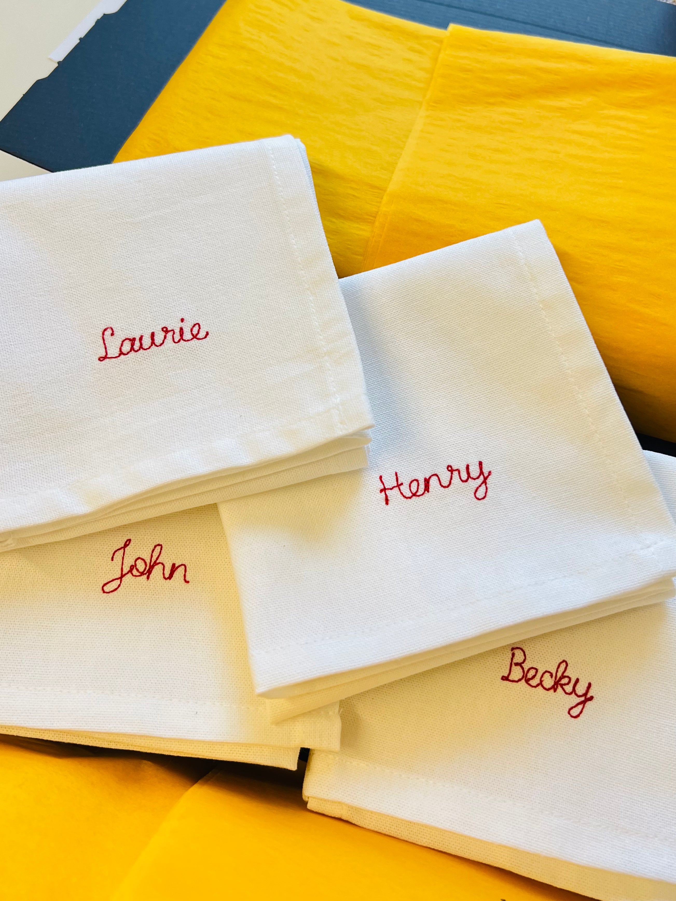a set of personalised embroidered family name napkins in red thread