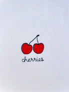 Cherry embroidery motif on white T-shirt, customizable with personal name or word in cursive script