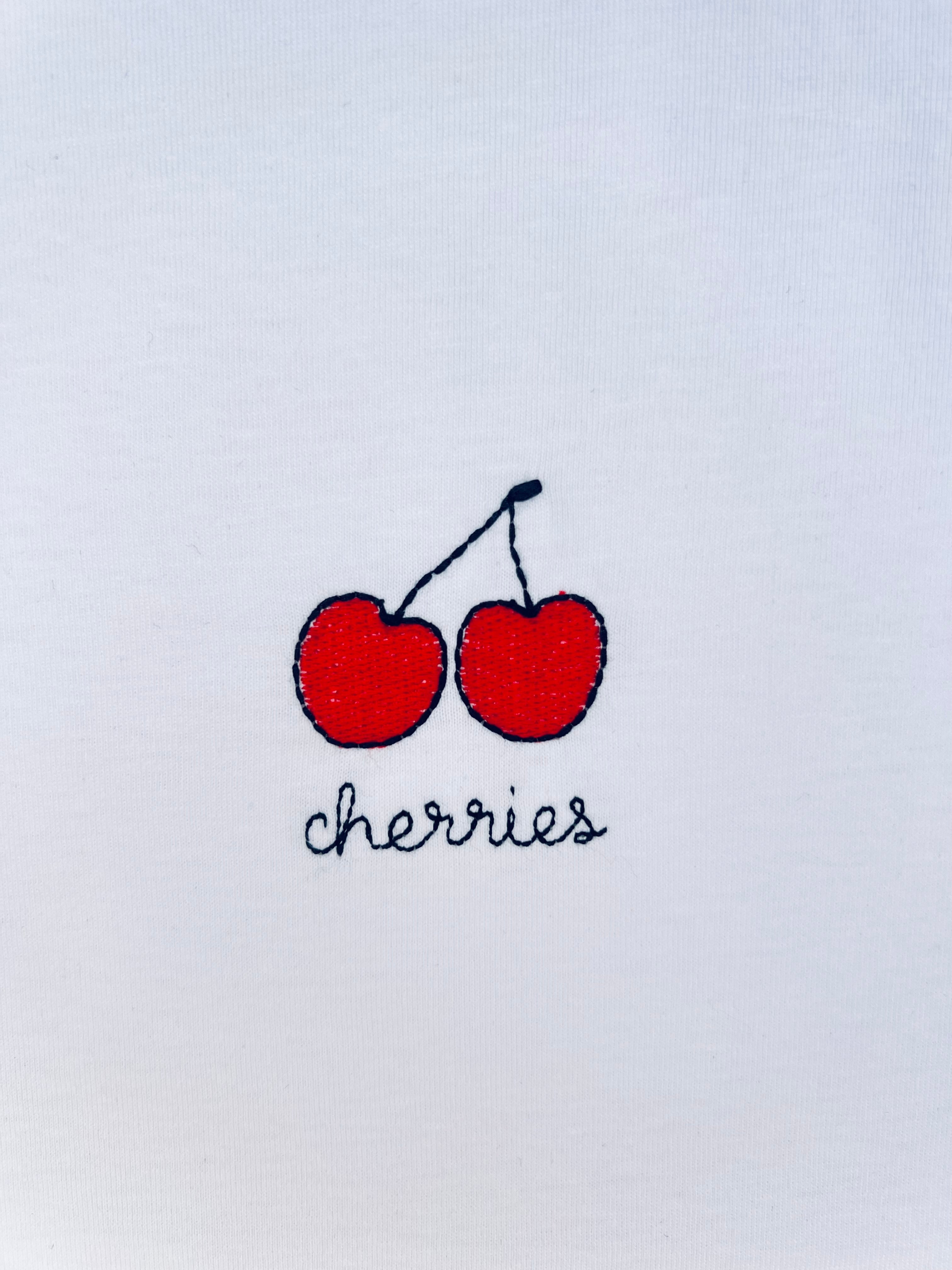 Cherry embroidery motif on white T-shirt, customizable with personal name or word in cursive script