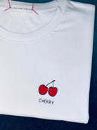 Cherry embroidery motif on white T-shirt, bespoke with personal name or word in block print