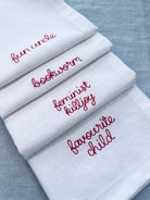 Custom embroidered napkins with family nicknames including favourite child, feminist killjoy, bookworm, fun uncle