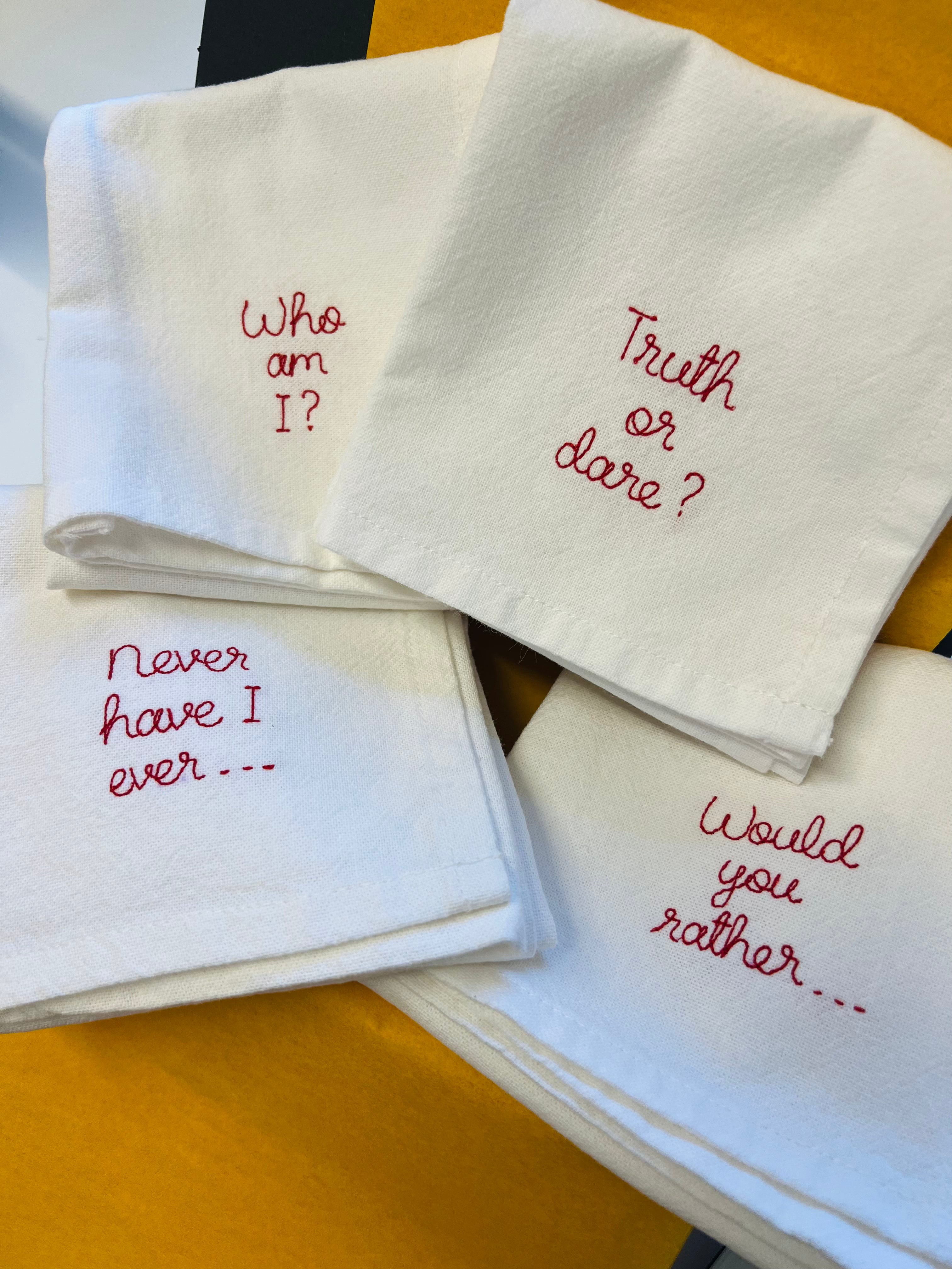 Set of four bespoke party games embroidered napkins with slogans such as ‘never have i ever’ and ‘would you rather’