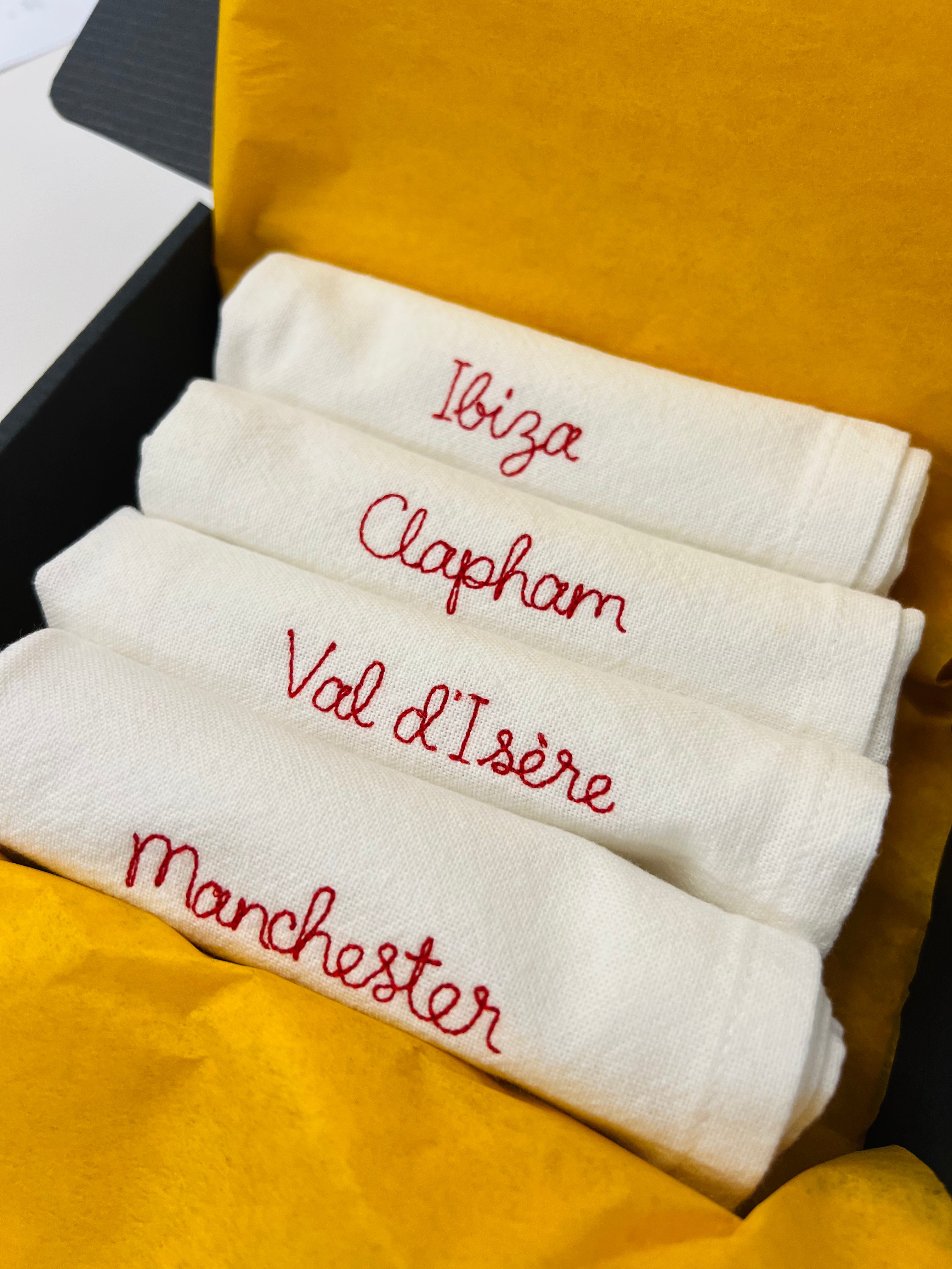 A set of embroidered napkins personalised with place names like Manchester, Ibiza, Clapham, val d’Isere