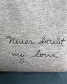 grey t-shirt with 'never doubt my love' embroidered in black thread, custom bespoke slogan embroidery