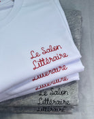 white and grey t-shirts with 'Le Salon Littéraire' embroidered in red and black thread, custom bespoke slogan embroidery