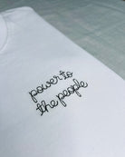 white t-shirt with 'power to the people' embroidered in black thread, custom bespoke slogan embroidery