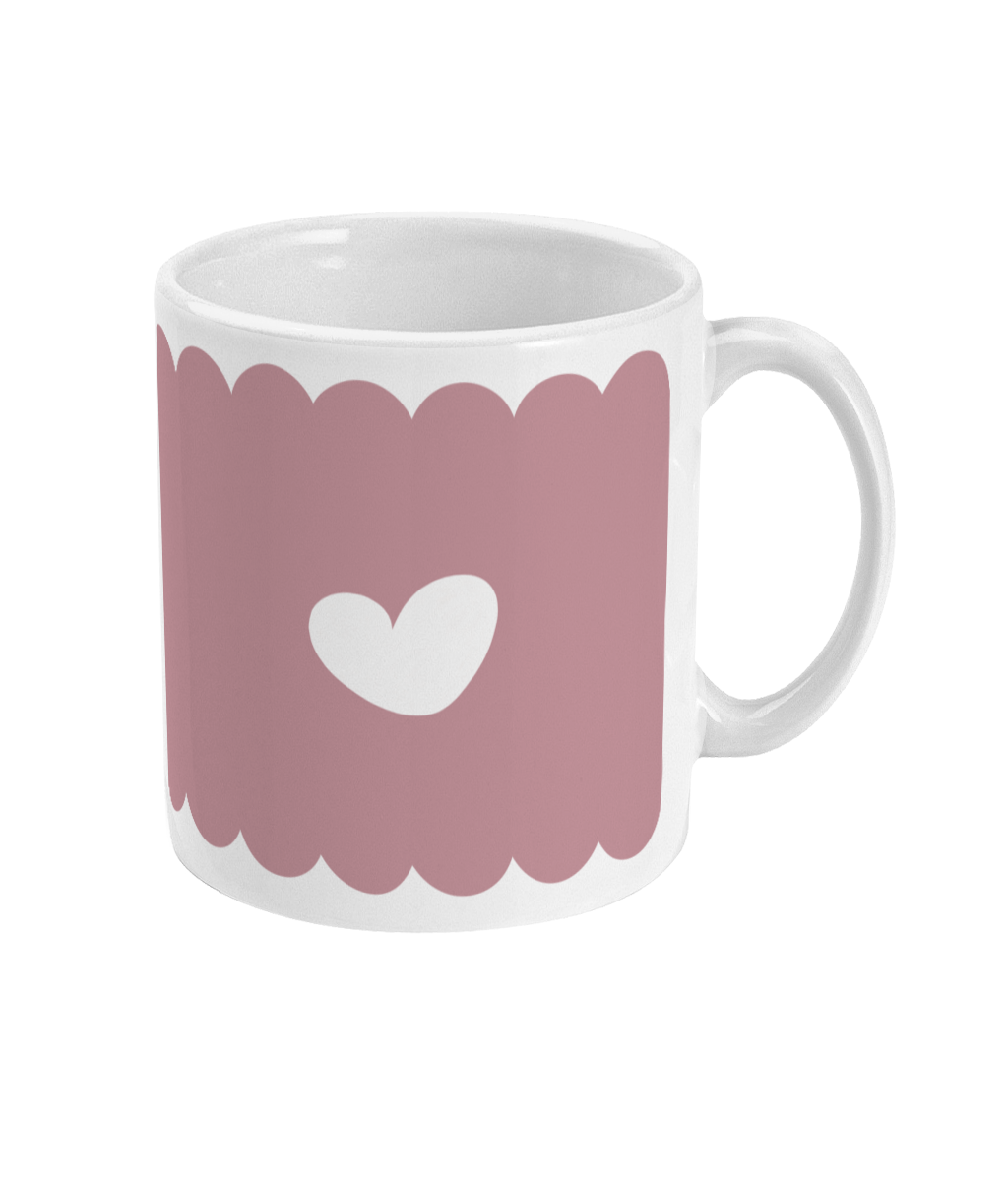 A ceramic mug with a soft pink background and a scalloped border, featuring a simple white heart design.