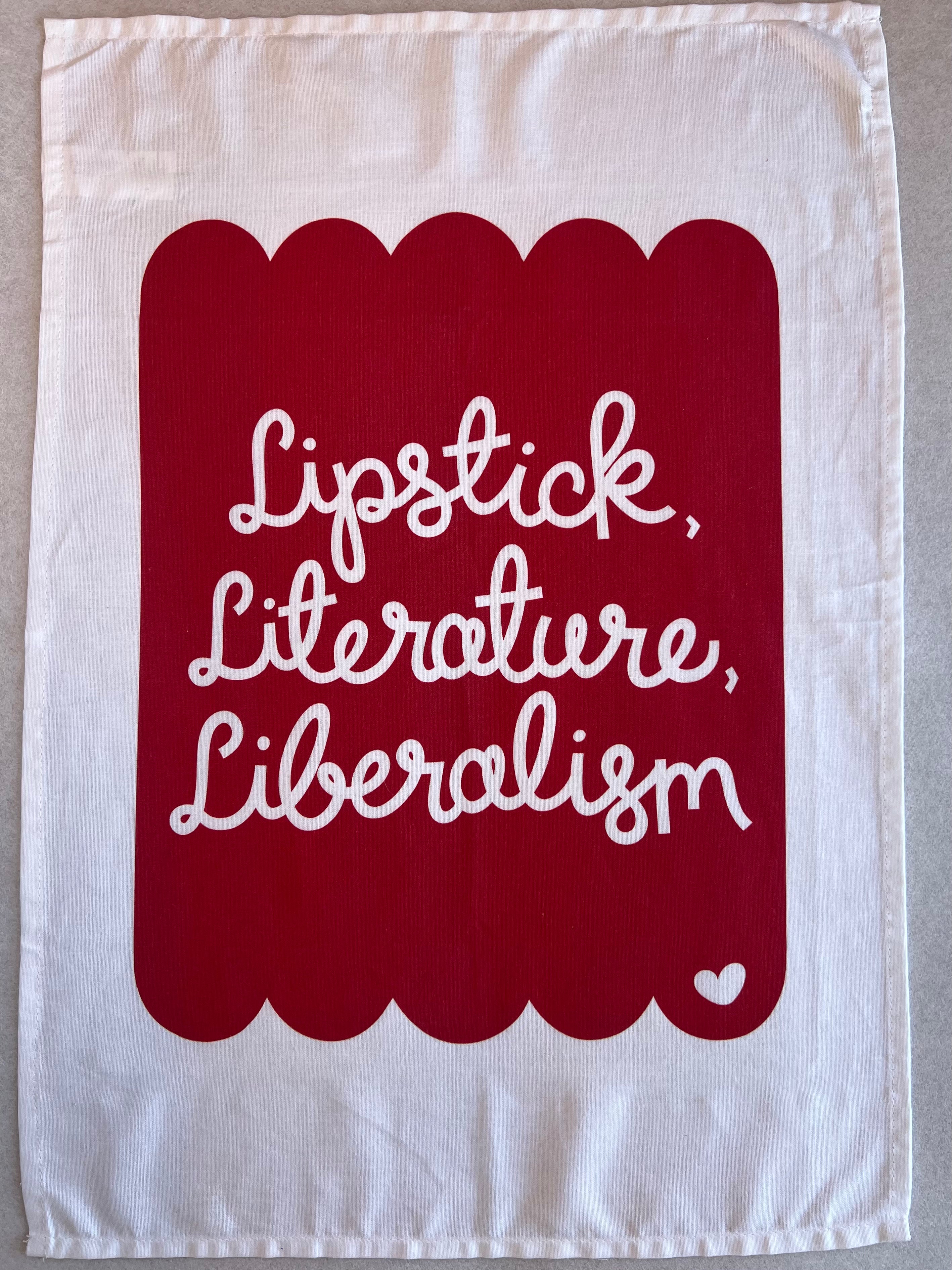 Cotton tea towel with a red scallop and heart design and the words lipstick, literature, liberalism 
