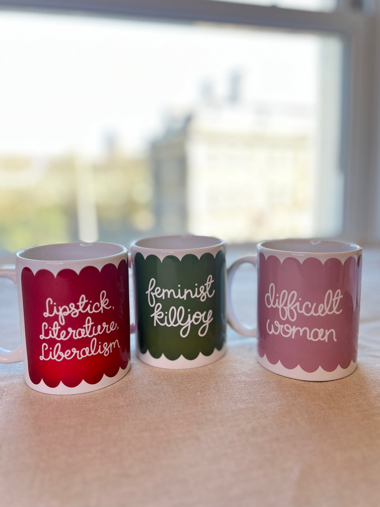 Three mugs in red, green, pink with scallop design featuring the phrases lipstick, literature, liberalism; feminist killjoy; difficult woman