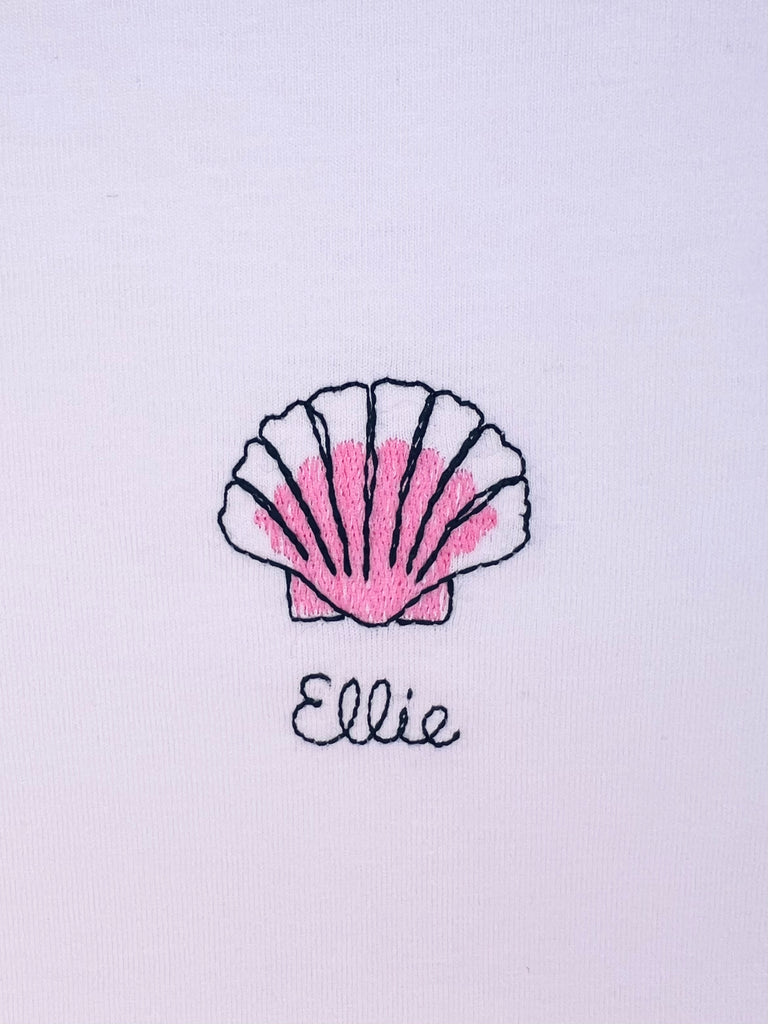 Shell embroidery motif on T-shirt with option to add custom name, perfect for beach lovers or coastal style